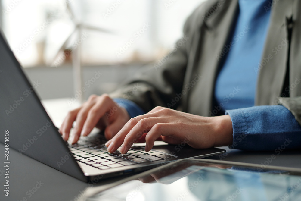 Hands of young unrecognizable businesswoman in smart casualwear touching keys of laptop keyboard during work over new project Hands of young unrecognizable businesswoman in smart casualwear touching keys of laptop keyboard during work over new project