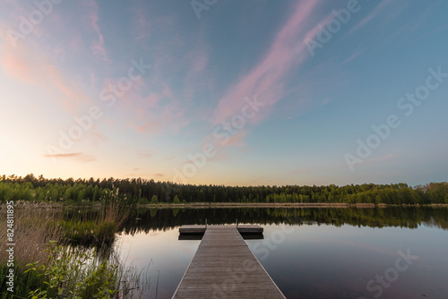 Wooden pier on the forest lake on spring evening