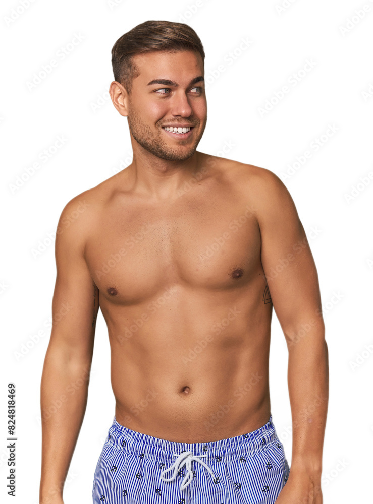 Young man shirtless in swimwear, studio looks aside smiling, cheerful and pleasant. Young man shirtless in swimwear, studio looks aside smiling, cheerful and pleasant.