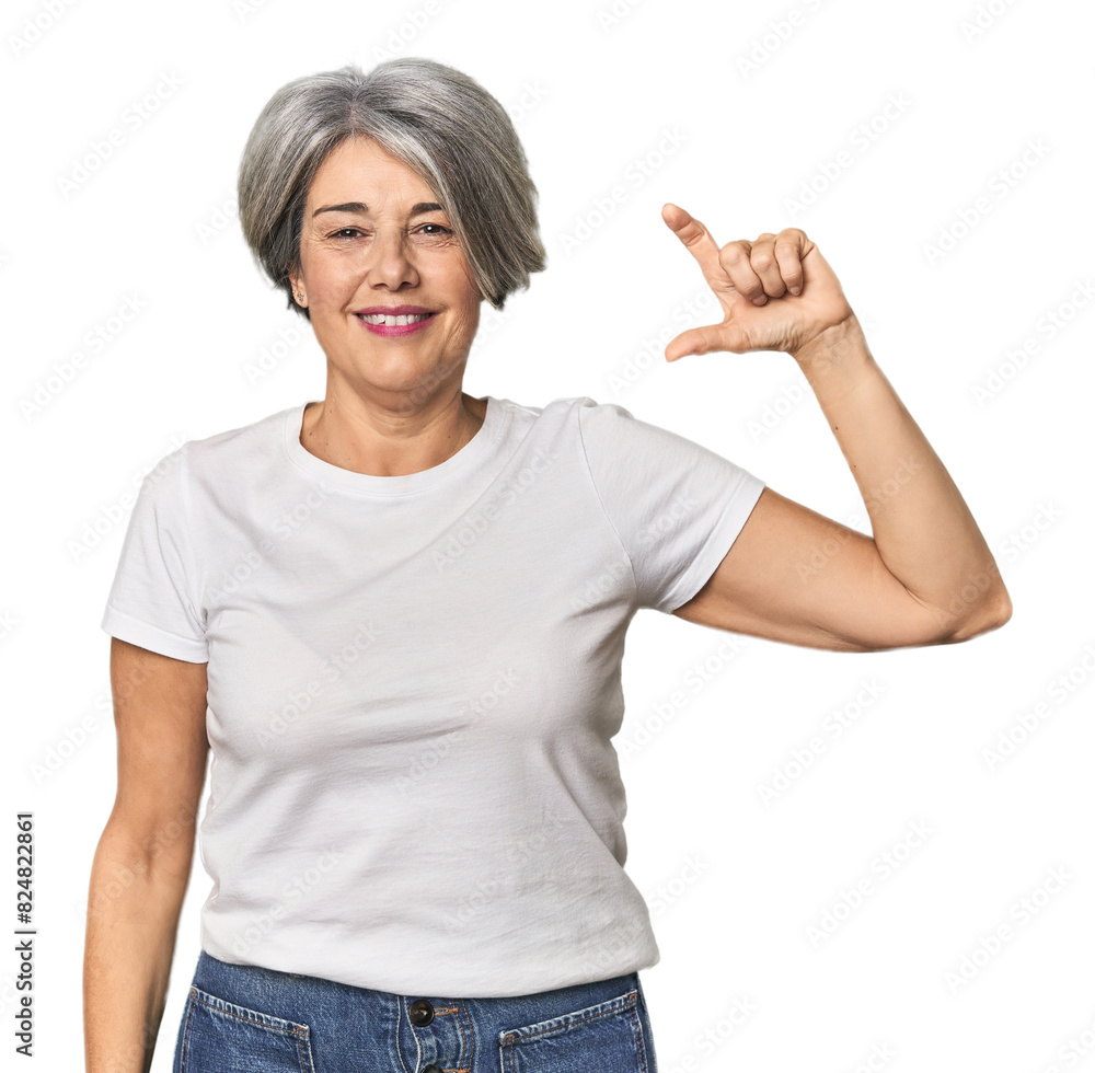 Fototapeta premium Caucasian mid-age female on studio background holding something little with forefingers, smiling and confident.