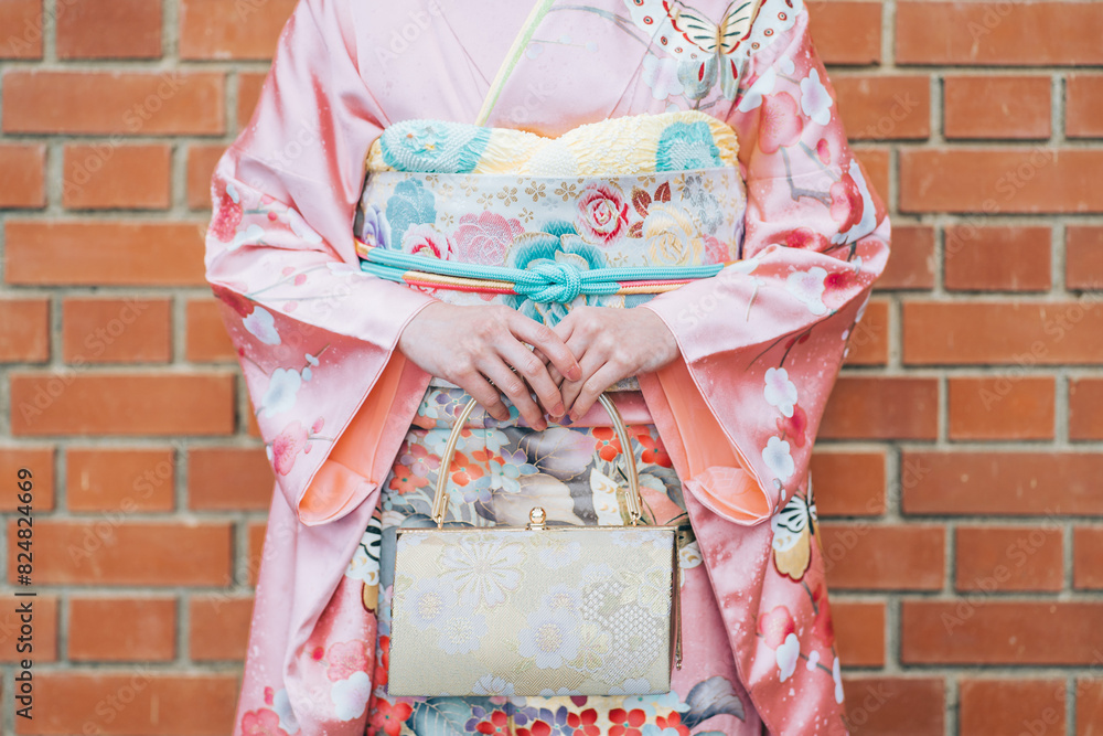 Naklejka premium 成人式、紅葉を背景にした振袖の女性の手元とバッグ