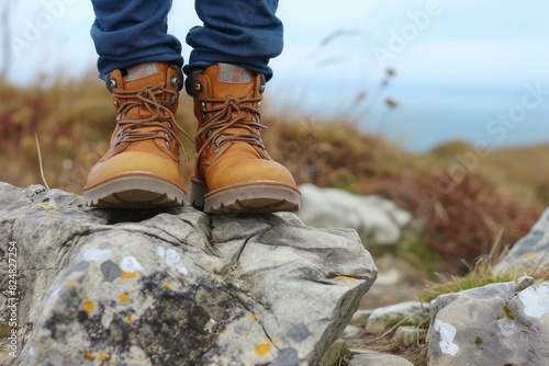 Close-up of hiker's booted feet dangling over a rocky trail with natural backdrop