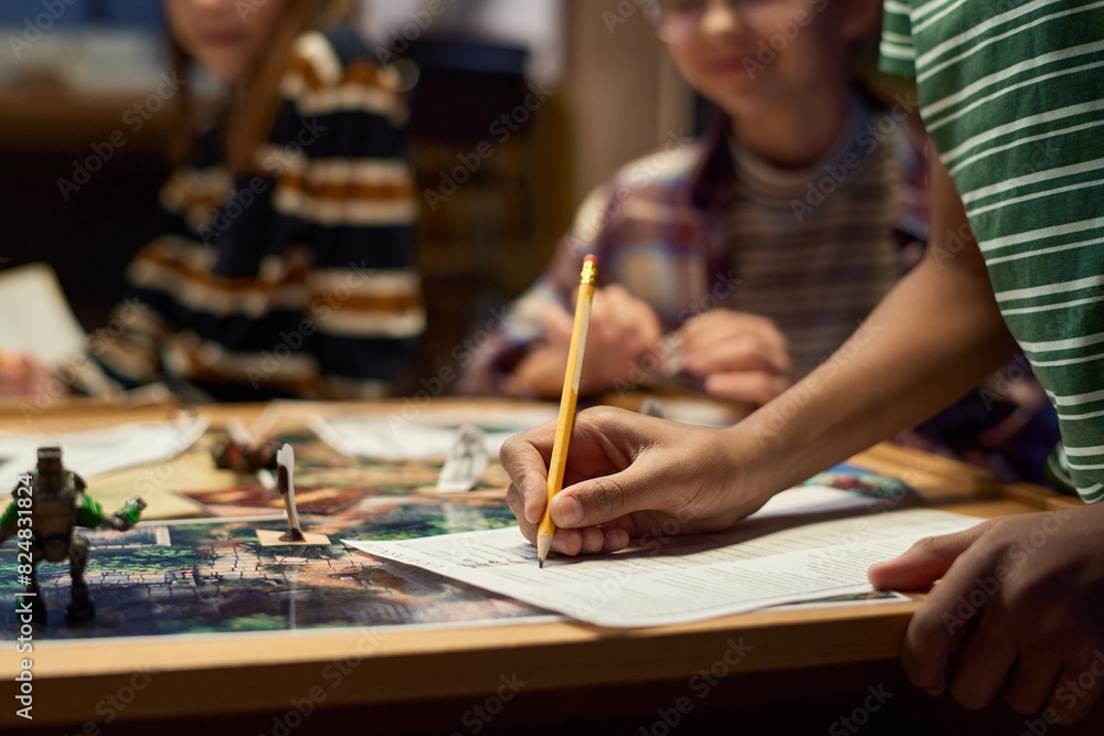 Hands of youngster pointing at paper with board game rules and ticking them while distributing roles among his friends before playing Hands of youngster pointing at paper with board game rules and ticking them while distributing roles among his friends before playing