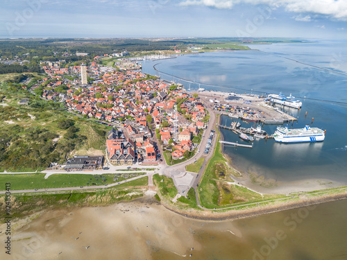 Aerial drone image of the historic Frisian town of West Terschelling on the Wad island in world heritage site Wadden Sea. Old brick lighthouse Brandaris and harbor with dunes, sandbanks and tidal sea photo