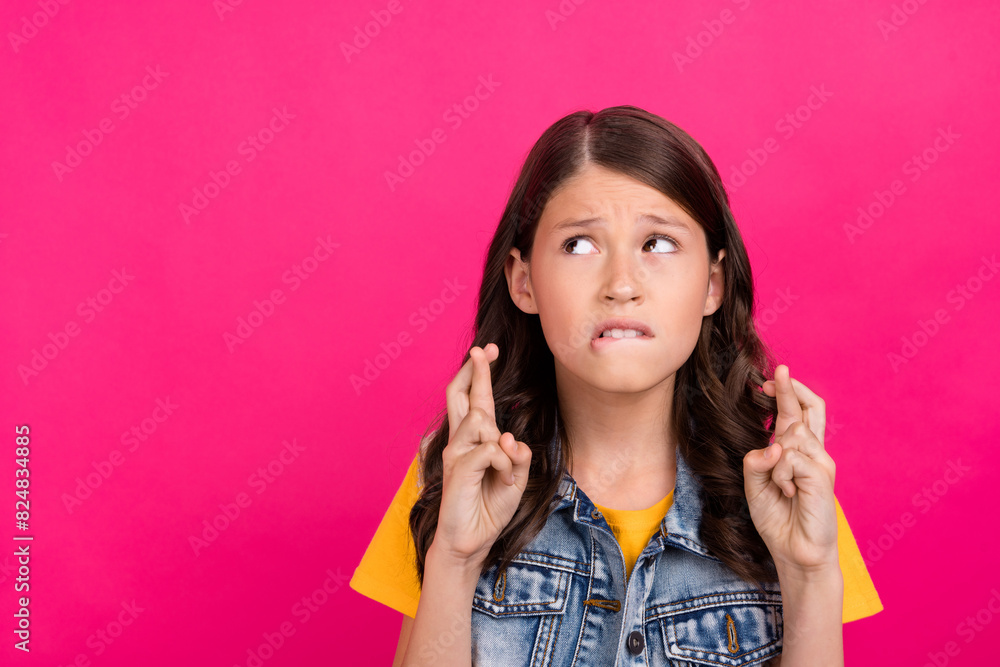 Photo of nervous kid girl cross fingers praying look empty space isolated bright color background Photo of nervous kid girl cross fingers praying look empty space isolated bright color background