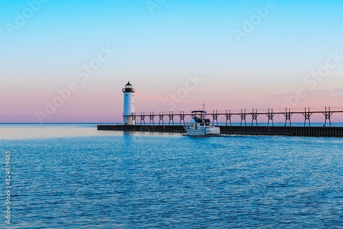 Boat moving down a channel next to a pier and lighthouse