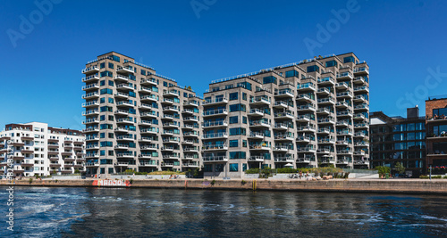 Moderne Wohnhäuser mit versetzten Balkonen am Hafen von Kopenhagen bei wolkenlosem Himmel
