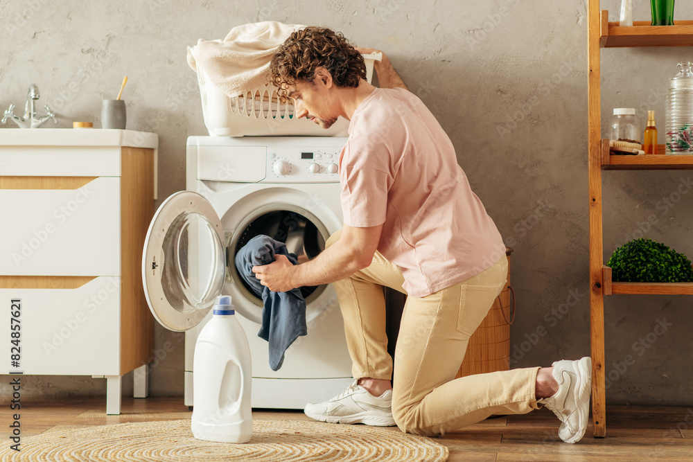 Man cheerfully loads clothes into washing machine. Man cheerfully loads clothes into washing machine.
