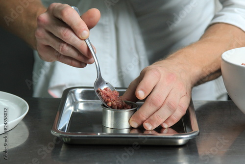 Chef's hands serving and decorating meal in restaurant kitchen