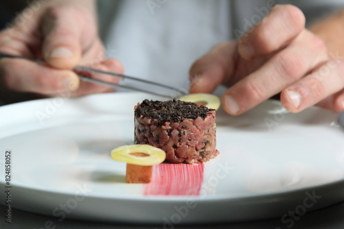 Chef's hands serving and decorating meal in restaurant kitchen