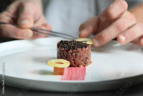 Chef's hands serving and decorating meal in restaurant kitchen