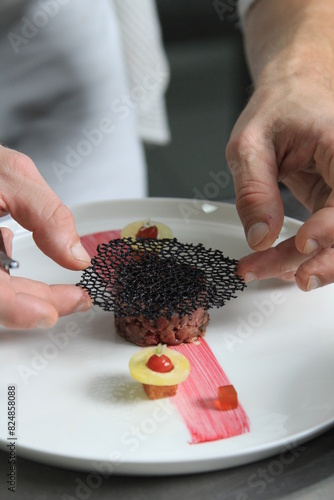 Chef's hands serving and decorating meal in restaurant kitchen