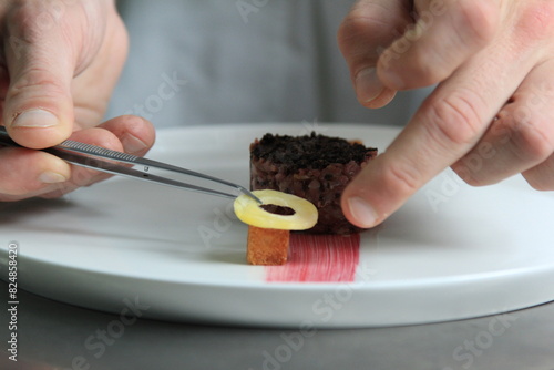 Chef's hands serving and decorating meal in restaurant kitchen