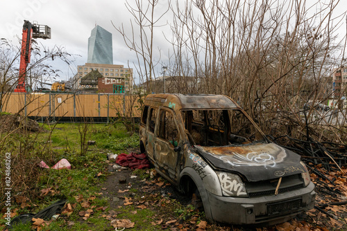 Verbranntes Auto auf verwilderter Baustelle mit Blick auf die EZB in Frankfurt