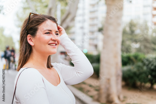Portrait of a female tourist who is walking in the city, smiling and wearing sunglasses