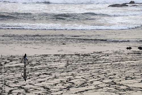 Woman Walking Along Textured Beach Shoreline
