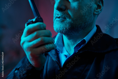 Canvas Print Cropped shot of mature male guard speaking to colleague in walkie-talkie while n
