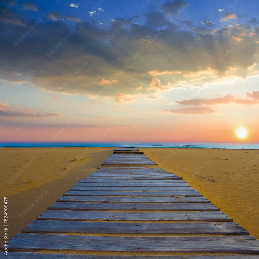 sandy sea beach with wooden street at the sunset