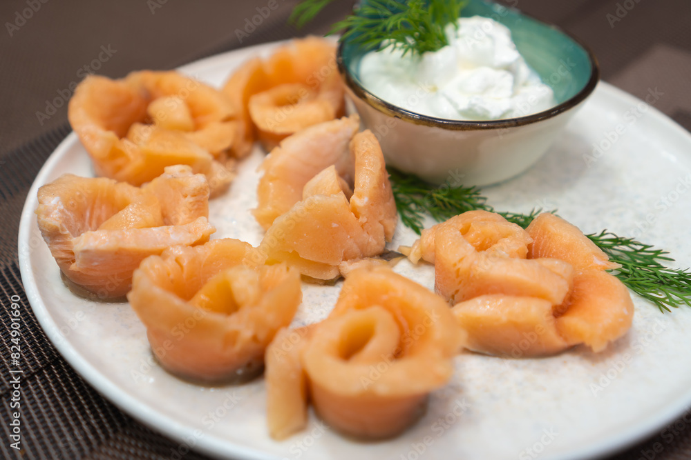Close-up of pickled salmon pieces on a white plate with sauce and dill on the table. Beautiful serving of pickled salmon Close-up of pickled salmon pieces on a white plate with sauce and dill on the table. Beautiful serving of pickled salmon