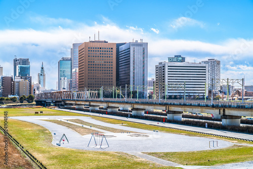 多摩川緑地公園（バイオリン公園）と川崎駅前のビル群の風景【神奈川県・川崎市 - 東京都・大田区】　The green space of the Tama River and the cityscape of Kawasaki - Kanagawa, Tokyo, Japan