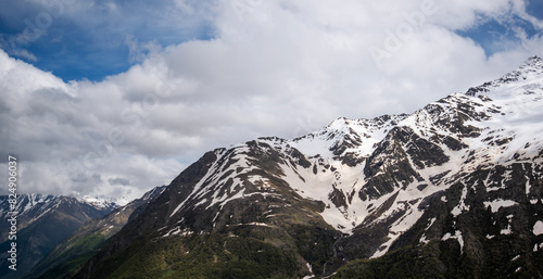 Summer view of the mountains with snowy peaks. Beautiful nature vacations, hiking, travel to nature destinations. View of the snowy rocky massif. Tourist attraction. World of beauty.