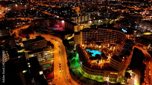 A short night-time drone video captures the lights of Maspalomas, Spain. The city glows like a gem, with bustling streets and bright lights creating a magical atmosphere under the starry sky.	 photo