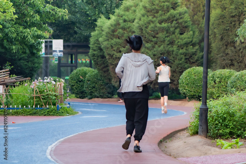 Tangshan City, Hebei Province, China: May 17, 2024- During holidays, in the blooming rose garden, people appreciate the roses and exercise by running