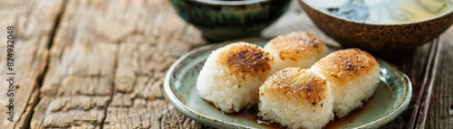 Yaki onigiri (grilled rice balls) served on a ceramic plate with soy sauce and miso soup photo