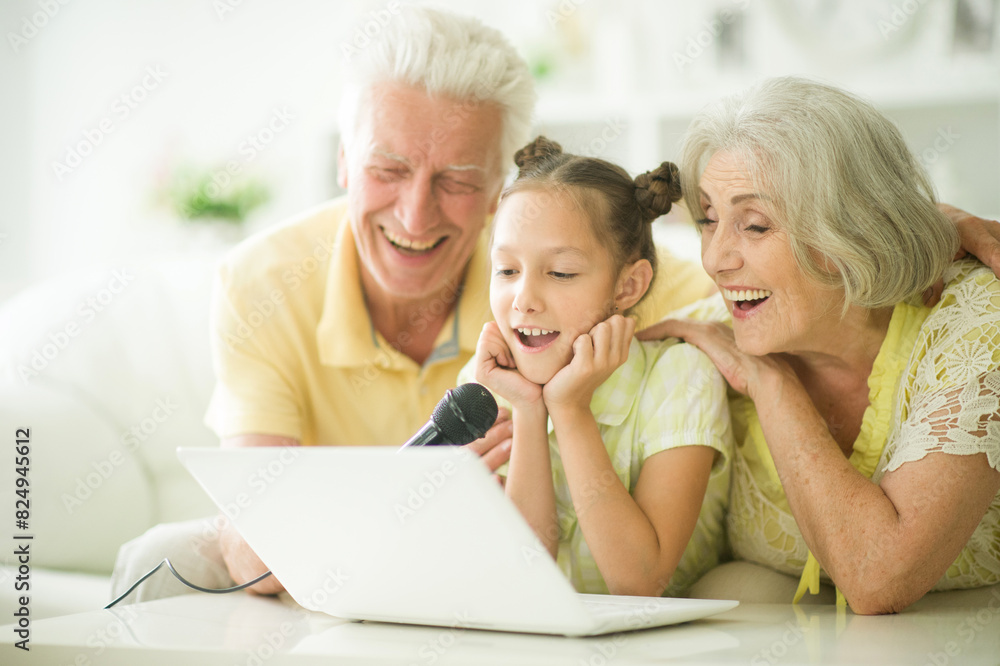 Portrait of grandparents with her granddaughter singing karaoke Portrait of grandparents with her granddaughter singing karaoke