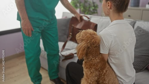 Hispanic male veterinarian in scrubs greeting a woman and her poodle in a cozy living room. photo