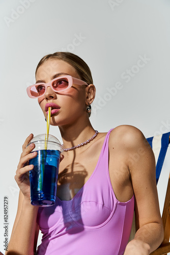 Trendy blonde woman in chic pink swimsuit enjoying a refreshing drink.