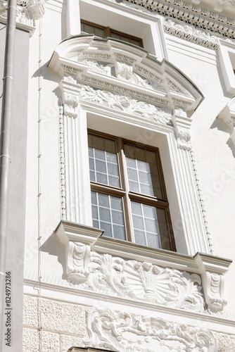 Ornate white baroque classical building facade with decorative stucco moldings framing arched window in historic European architecture