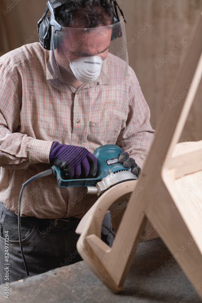 Making furniture. Carpenter sanding wooden chair with grinder in furniture factory Making furniture. Carpenter sanding wooden chair with grinder in furniture factory