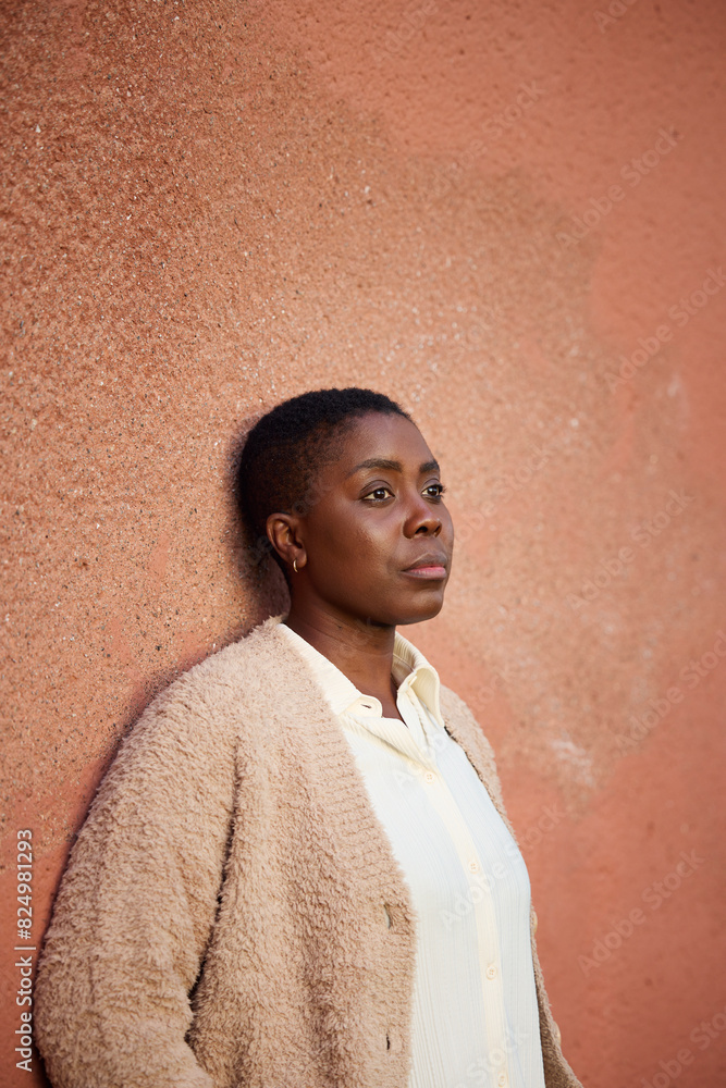 Contemplative mature woman looking away while standing against wall Contemplative mature woman looking away while standing against wall