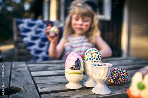 Colorful Easter eggs in containers on table while girl in background photo