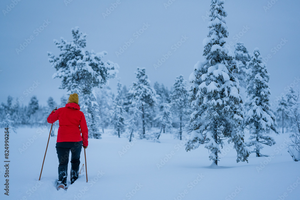 Rear view of woman with ski poles hiking on snow covered land during vacation Rear view of woman with ski poles hiking on snow covered land during vacation