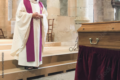 A priest in a church cassock conducts a funeral service in a French church photo