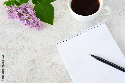 a notebook with a pen and a cup of coffee and branch of lilac