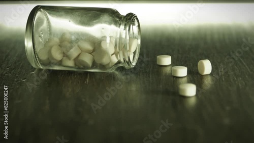 Bottle of pills fall on a table. A medical, nutrition or social issues concept. photo