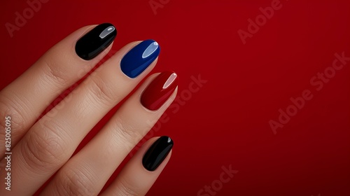 Close-up of a hand with elegant multicolored nail polish on a vibrant red background  showcasing stylish manicure trends.
