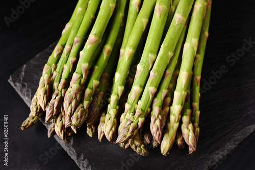 Top view of fresh green asparagus on black background