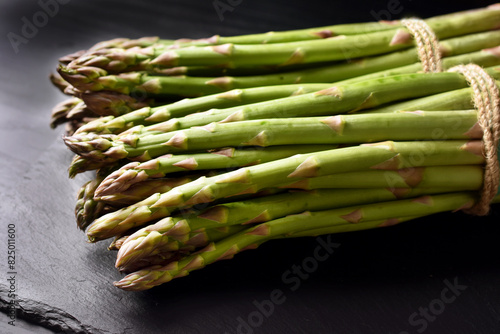 Two bunches of fresh green asparagus on black background