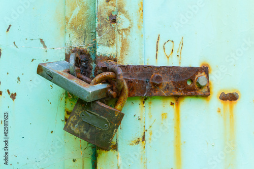 A detailed close-up of two rusty padlocks securing an old, weather-worn metal door, symbolizing security, age, and decay.