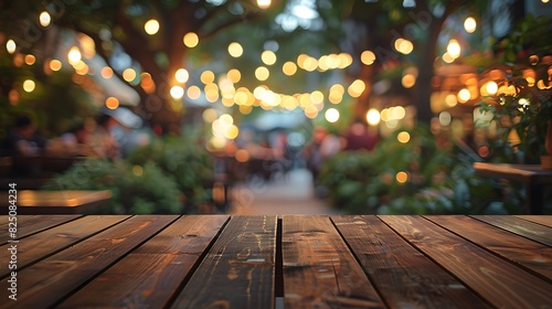 Empty wooden table top with blurred background of outdoor restaurant in the evening for product display montage. 