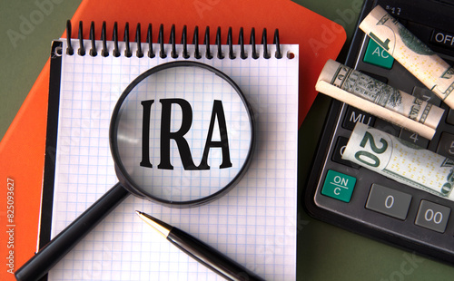 Obraz na płótnie IRA - acronym under magnifying glass on the background of calculator and banknot