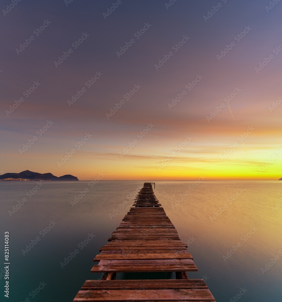 sunrise seascape with an old wooden dock leading out into the calm ocean waters sunrise seascape with an old wooden dock leading out into the calm ocean waters