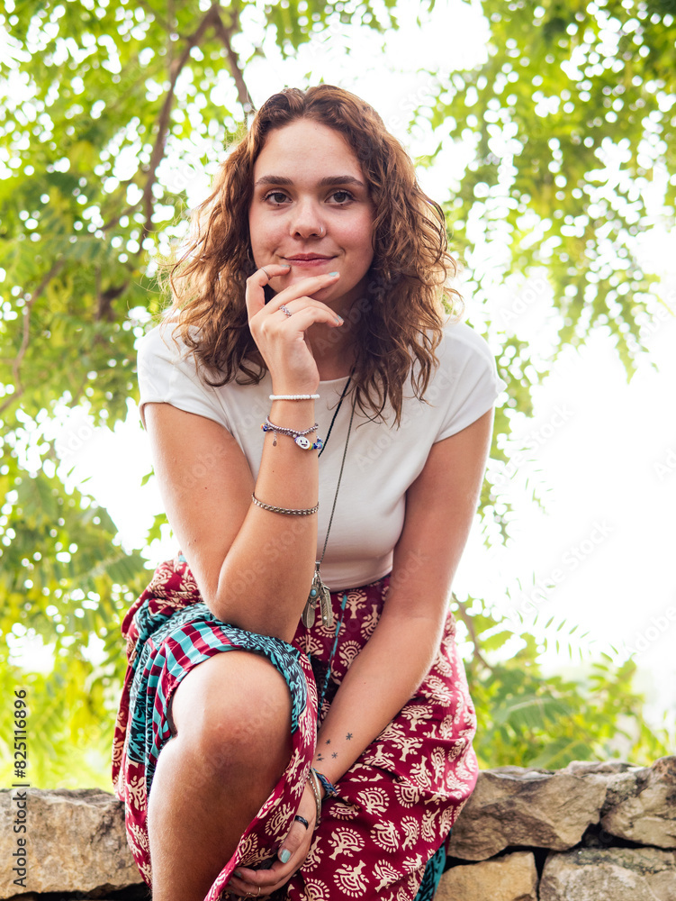 Young Woman Relaxing on a Stone Wall in a Summer Park During the Afternoon Young Woman Relaxing on a Stone Wall in a Summer Park During the Afternoon