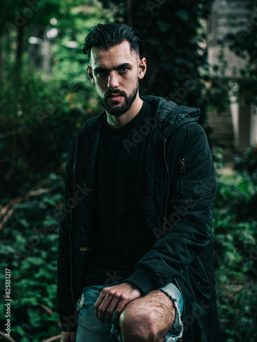 Pensive Young Man in a Forest at Dusk Wearing a Black Jacket

