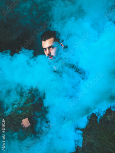 Young Man Surrounded by Colorful Smoke in a Dark Outdoor Setting at Night