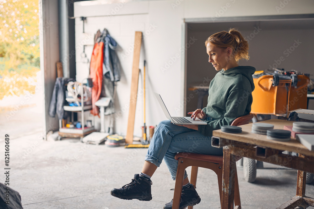 Female Worker In Concrete Workshop Using Laptop Computer